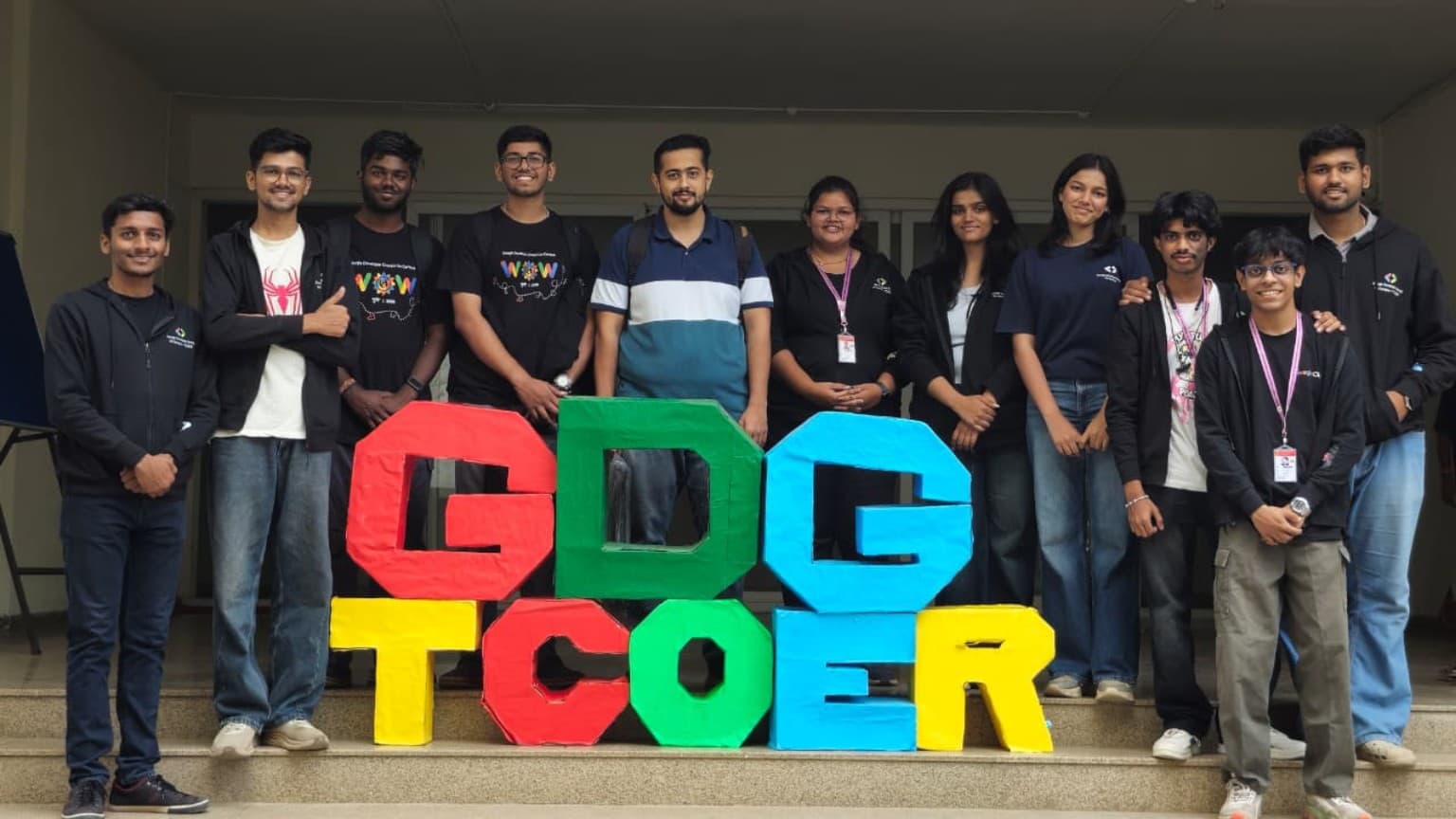 Google Developer Group on Campus TCOER core team standing together behind the colorful GDG TCOER installation